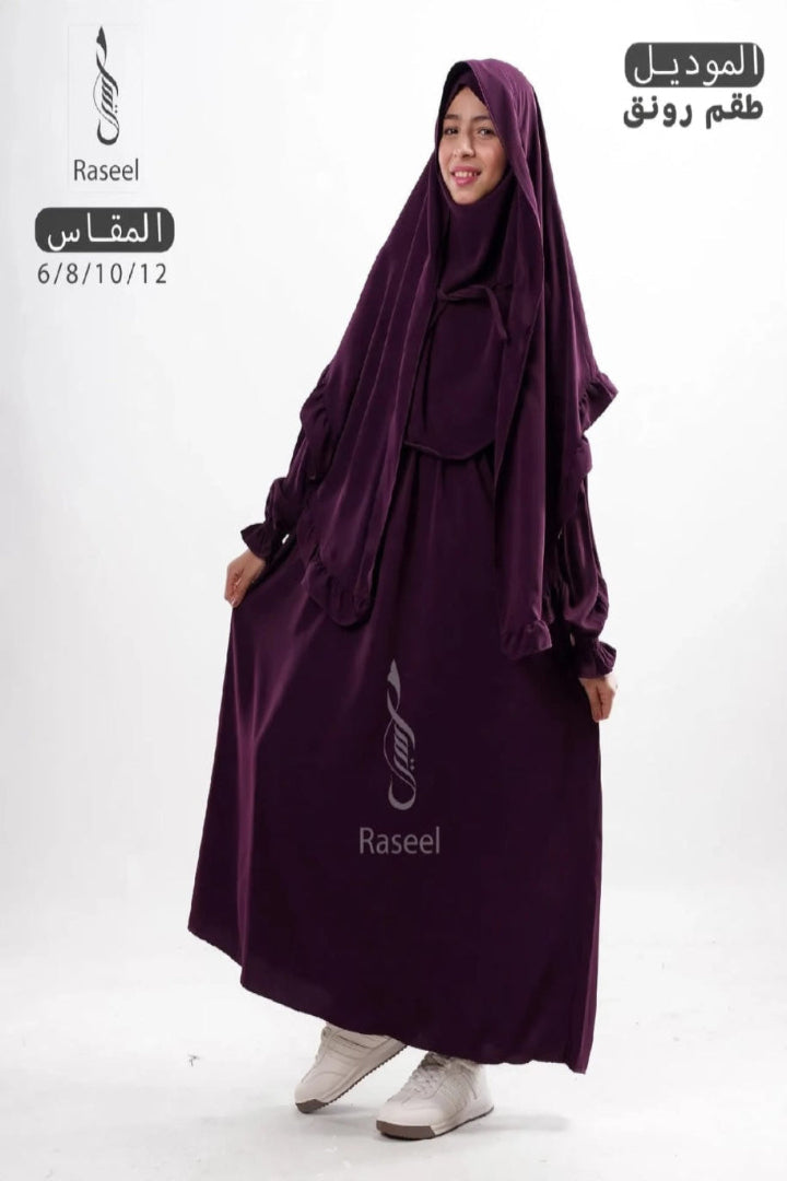 A woman modeling a deep purple Islamic modest clothing set, including a long abaya dress and matching hijab, against a plain white background. Arabic text overlays for the product are visible on the top left and top right.