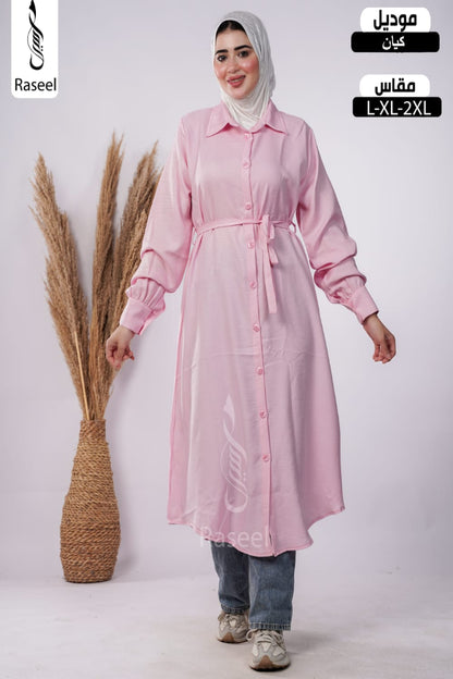 A woman wearing a light pink long-sleeve button-front tunic dress with a tie waist, styled with a white hijab, blue jeans, and sneakers. The image has 'Raseel' branding and Arabic text indicating the product is a tunic with a matching seat pad, sizes L-XL-2XL.